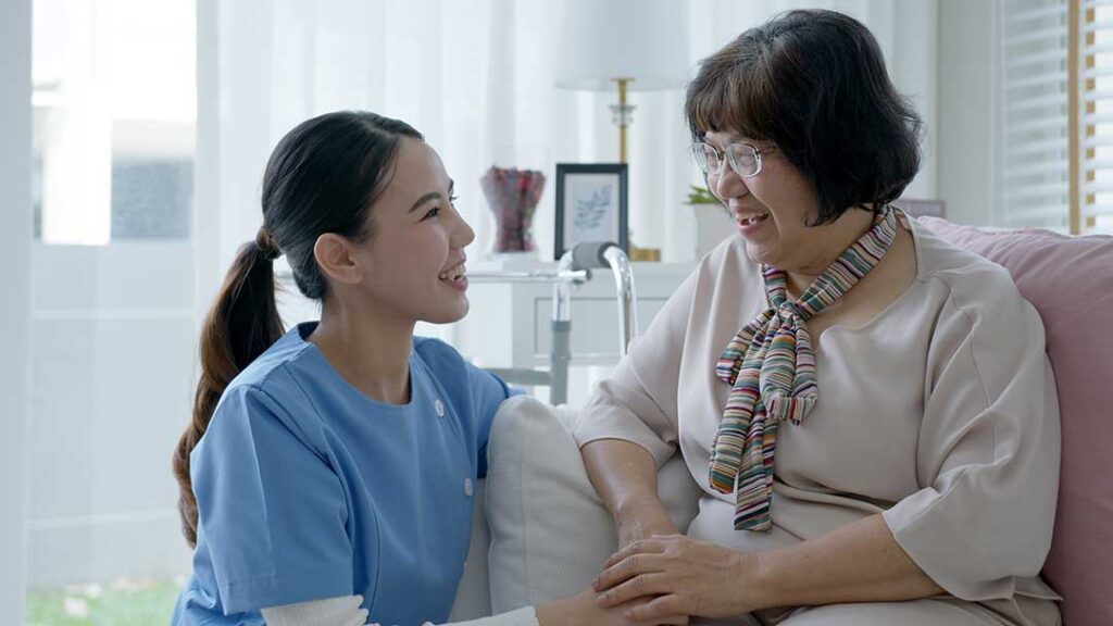 Older adults walking with a caregiver in a well-lit hallway equipped with grab bars and clear pathways.