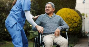 Older adult in assisted living using a tablet with a family video call and written instructions nearby